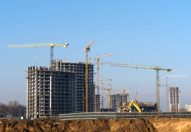 istock Tower cranes constructing a new residential building at a construction site against blue sky. Renovation program, development, concept of the buildings industry. 1218541126