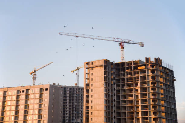 istock Tower cranes and builders in action on blue sky background 1218541330