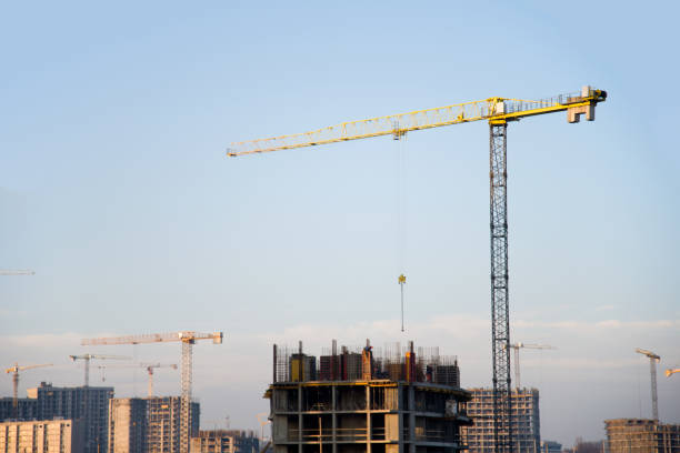 istock Tower crane and builders in action on blue sky background 1218541522