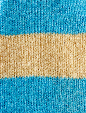 fragment of knitted fabric from blue and beige wool, pigtail pattern