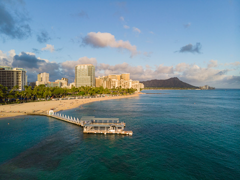 Capture the beauty of Hawaii's famous Waikiki Beach at sunset with this digital photo. This stunning image features the golden glow of the sun.