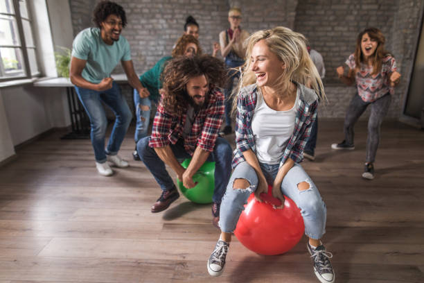 istock Joyful freelance workers having fun in space hopper challenge at casual office. 1218547424