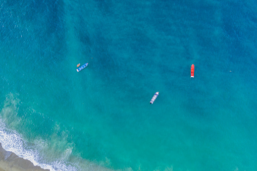 Artisanal fishing boats anchored near the shore of a beach in the Caribbean Sea.