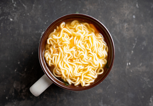 Instant noodles in cup on the rustic background. Selective focus. Shallow depth of field.