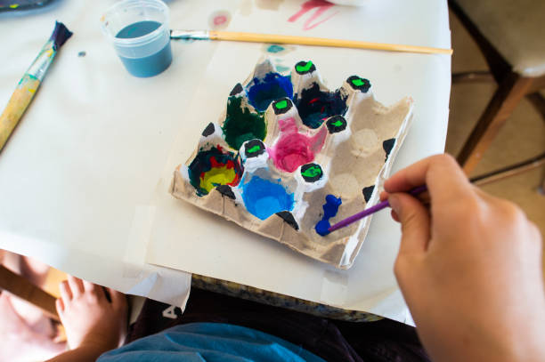 istock Home school art and craft class painting Easter egg holders with bright colours personal perspective 1218550100