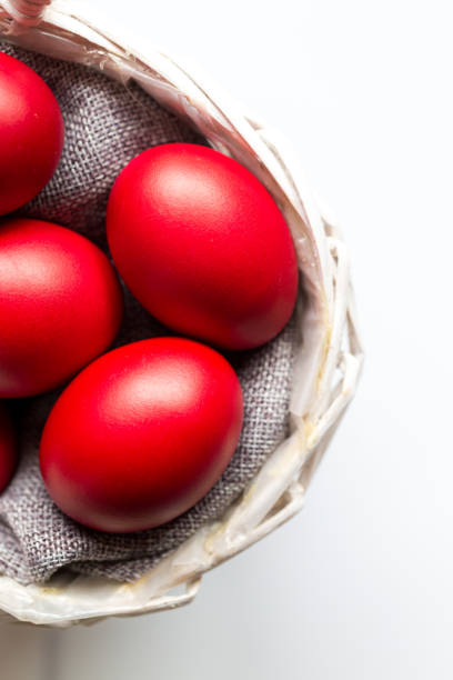 Red Painted Easter eggs on white wood background Color image depicting an overhead view of an Easter-themed flat lay on a white wooden background. A basket of red painted eggs is in the foreground, with the white wooden surface defocused beyond. orthodox church easter stock pictures, royalty-free photos & images