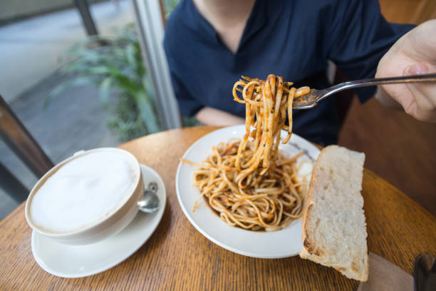 Woman eating Itlian spaghetti pasta with fork, close up macro