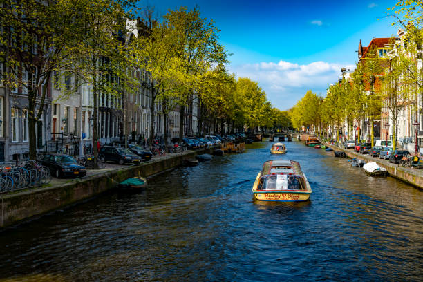 Canal during a bright spring day in Amsterdam, Netherlands with a tour boat on the canal.