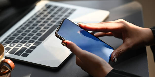 istock Cropped image of hands holding a empty screen smartphone over computer laptop and coffee cup as background. Orderly workspace concept. 1218554442