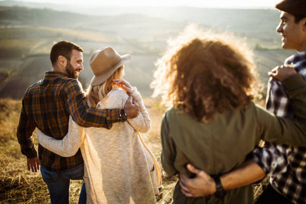 istock Rear view of happy embraced couples walking in a meadow. 1218554690