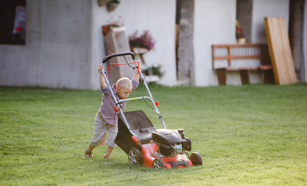 istock Down syndrome child with lawn mower walking outdoors in garden. 1218555018