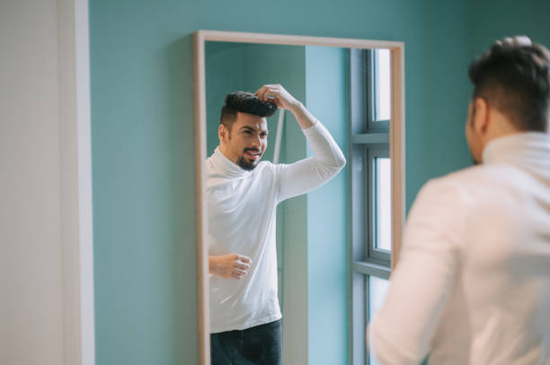 istock a middle eastern man looking at mirror reflection dress up turtleneck shirt smart casual getting ready self love 1218555540