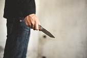 Close up of man holding knife in abandoned house. Terrorist and Robber concept. Police and Soldier. Weapon and armed theme