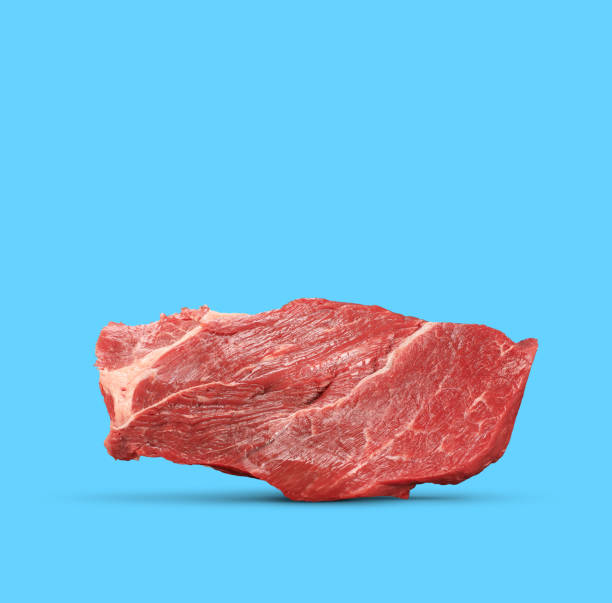 istock raw red beef meat isolated on a blue background 1218556409