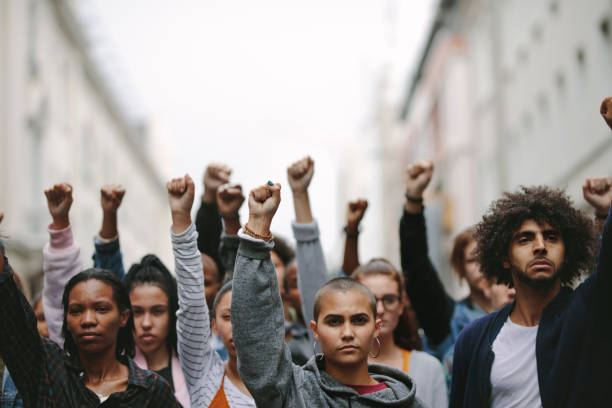 Activists protesting on the street Group of protestors with their fists raised up in the air. Activists protesting on the street. gen z stock pictures, royalty-free photos & images