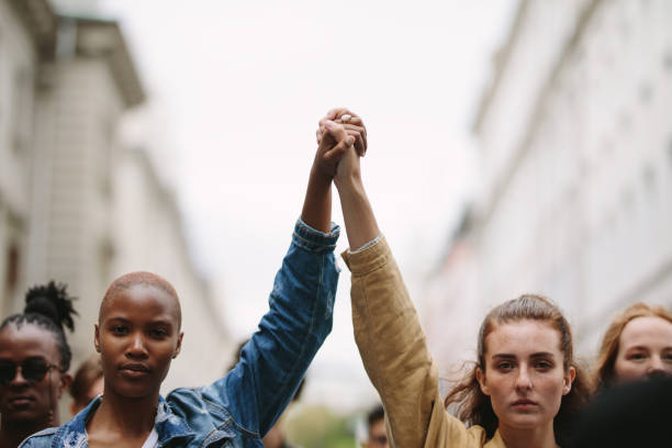 group of activists with holding hands protesting - solidariedade imagens e fotografias de stock