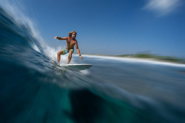 長い髪を持つ若い男のサーファーは、モルディブで速く、完璧な海の波をサーフィン - splashing maldives human hair spray スト�ックフォトと画像