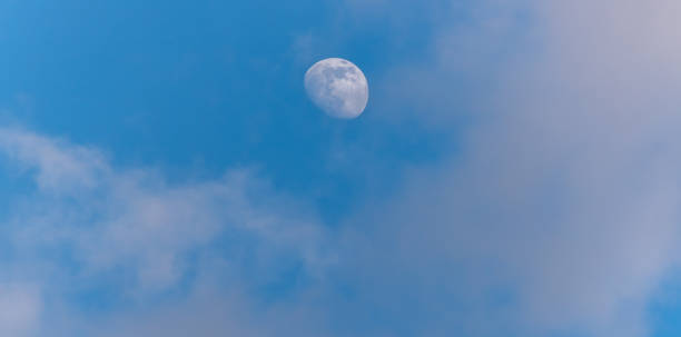 istock Three Quarter Moon in a Blue Sky with Clouds 1218561089