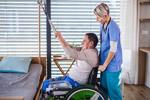 A healthcare worker and senior patient in wheelchair, physiotherapy concept.