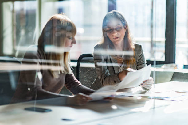 istock Young businesswomen reading reports at corporate office. 1218571317