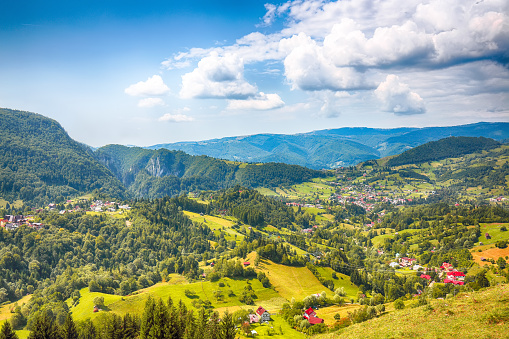 Stunning alpine landscape with green fields and Piatra Craiului mountains in Dambovicioara Commune. Location: Podu Dambovitei village, Arges County, Dambovicioara Commune, Romania, Europe