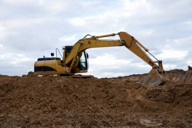 istock Excavator at earthworks on construction site. Backhoe loader digs a pit for the construction of the foundation. Digging trench for laying sewer pipes drainage in ground. Earth-Moving Heavy Equipment 1218571761