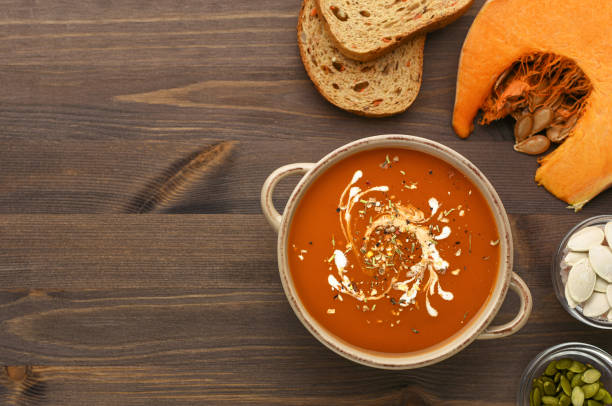 istock Pumpkin soup puree decorated with cream on wood background top view. 1218573396