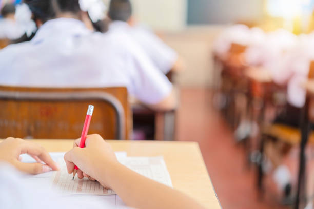 soft focus.high school holding pencil writing on paper answer sheet soft focus.high school holding pencil writing on paper answer sheet.sitting on lecture chair taking final exam attending in examination room or classroom.student in uniform. business teaching student writing stock pictures, royalty-free photos & images