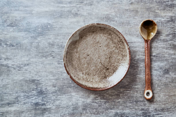 istock Empty ceramics plate and spoon on rustic wooden background. Top view. Copy space. 1218578733