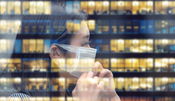 donna asiatica con maschera facciale che torna al lavoro, edificio aziendale che riflette - istockalypse foto e immagini stock