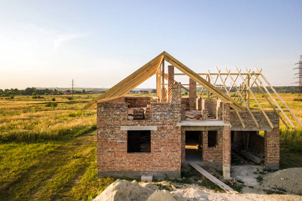 istock Unfinished brick house with wooden roof structure under construction. 1218582783