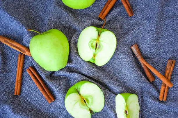 green golden apples or Granny smith with cinnamon sticks on kitchen towel, preparing food, dessert, healthy nutrition, autumn time