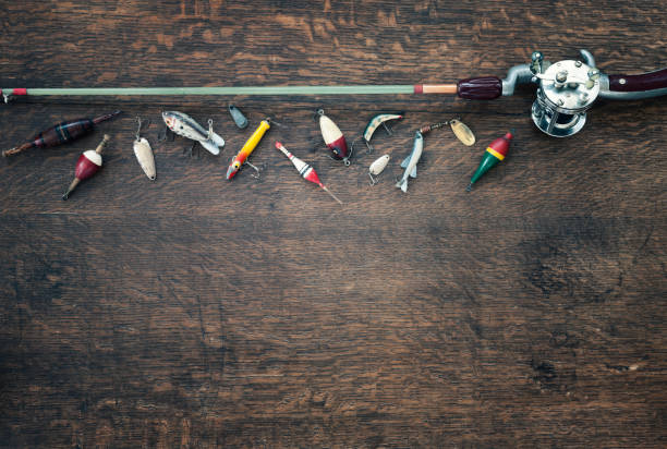 Fishing Background Vintage fishing rod, reel, line and lures/tackle on an old wood background wooden spool stock pictures, royalty-free photos & images