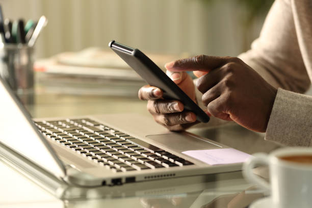 istock Black man hands using phone with laptop at home 1218586036