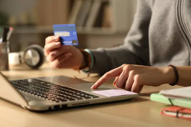 Photo of Student hands paying with credit card on laptop at night