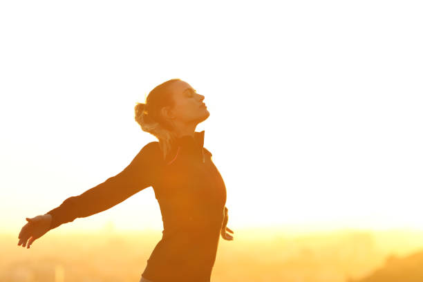 Runner resting breathing fresh air at sunset Profile of a runner resting breathing deeply fresh air outstretching arms at sunset inhaling stock pictures, royalty-free photos & images