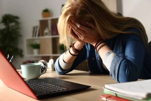 Photo of Sad student receiving bad news on laptop at night