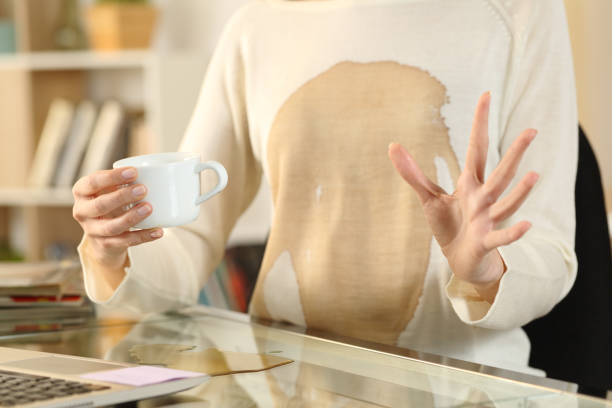 シャツの上にこぼれたコーヒーを持つ女性の手 - spilling ストックフォトと画像