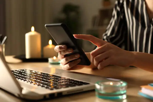 Photo of Girl hands using phone on power outage with candles