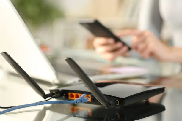 Photo of Woman using multiple devices with broadband router on foreground