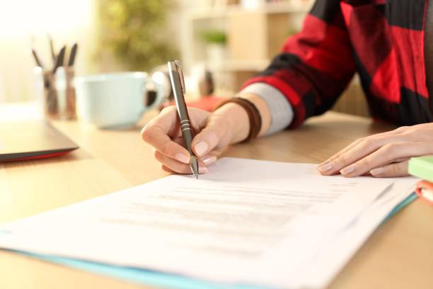 la fille d’étudiant mains signent le contrat sur un bureau - application form photos photos et images de collection