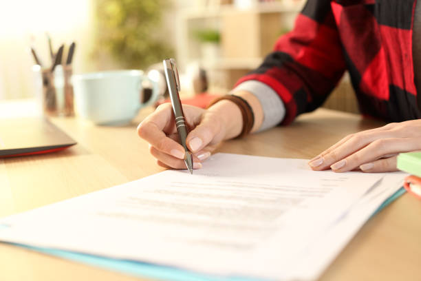 Student girl hands signing contract on a desk Close up of student girl hands signing contract on a desk at home permission concept photos stock pictures, royalty-free photos & images