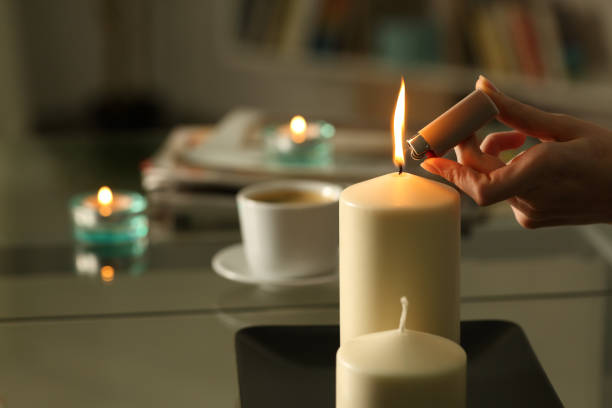 Woman hand lighting candles with lighter at night Close up of woman hand lighting candles with lighter in the night at home on a power outage cigarette lighter stock pictures, royalty-free photos & images