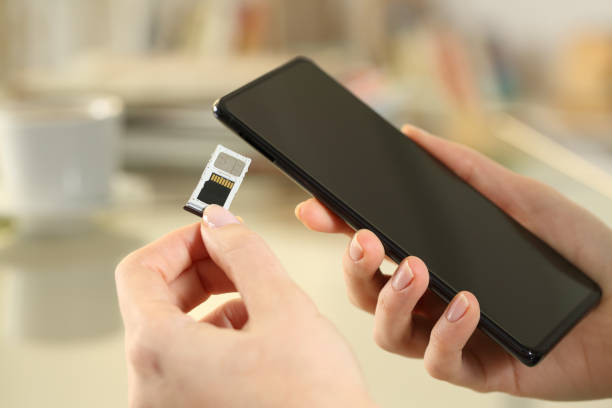 girl hand inserting sim and sd card on smart phone - memory card imagens e fotografias de stock