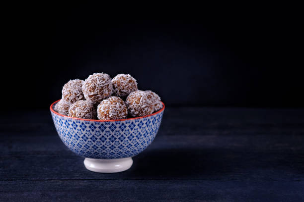 istock A bowl with coconut chocolate energy balls on dark background with copy space. Horizontal orientation 1218591710
