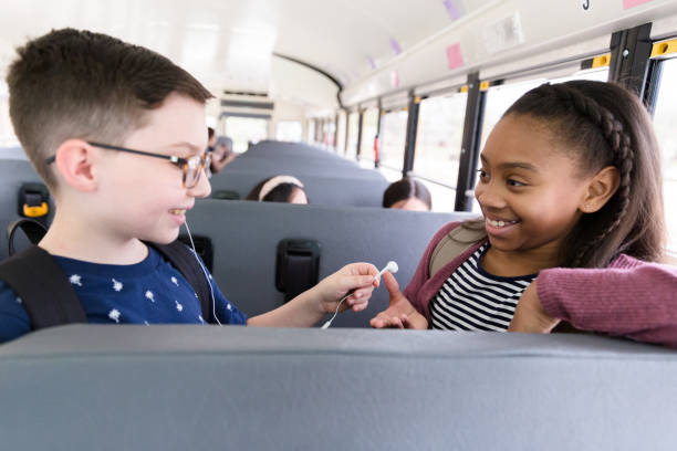 istock On school bus, boy shares earbuds with female classmate 1218592543