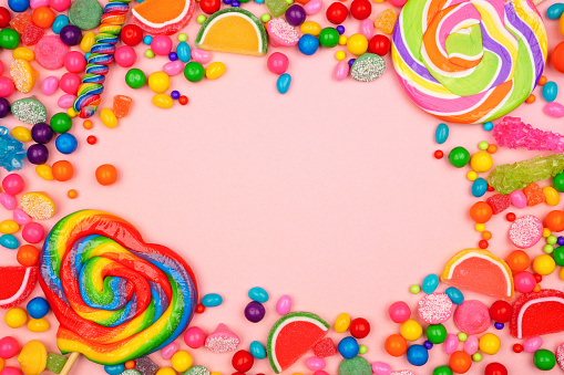 Colorful assortment of candies. Top view frame over a pink background.