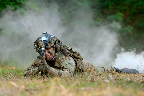 Beautiful woman soldier lie on ground and point gun to target direction with concept of woman fight in battle field Beautiful woman soldier lie on ground and point gun to target direction with concept of woman fight in battle field. female combat soldier stock pictures, royalty-free photos & images