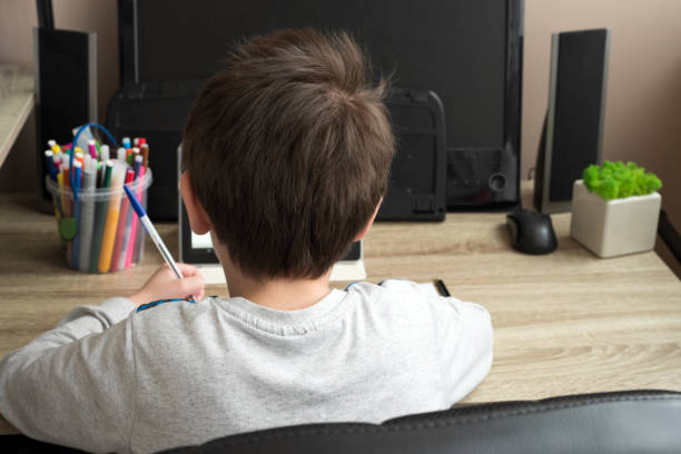 istock Boy studying at home with tablet and doing school homework. Distance learning online education or stay at home concept. Soft focus. Back view 1218604069