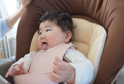 Bebé de 5 meses de edad sentado en una silla de bebé después de comer comida para bebés. photo